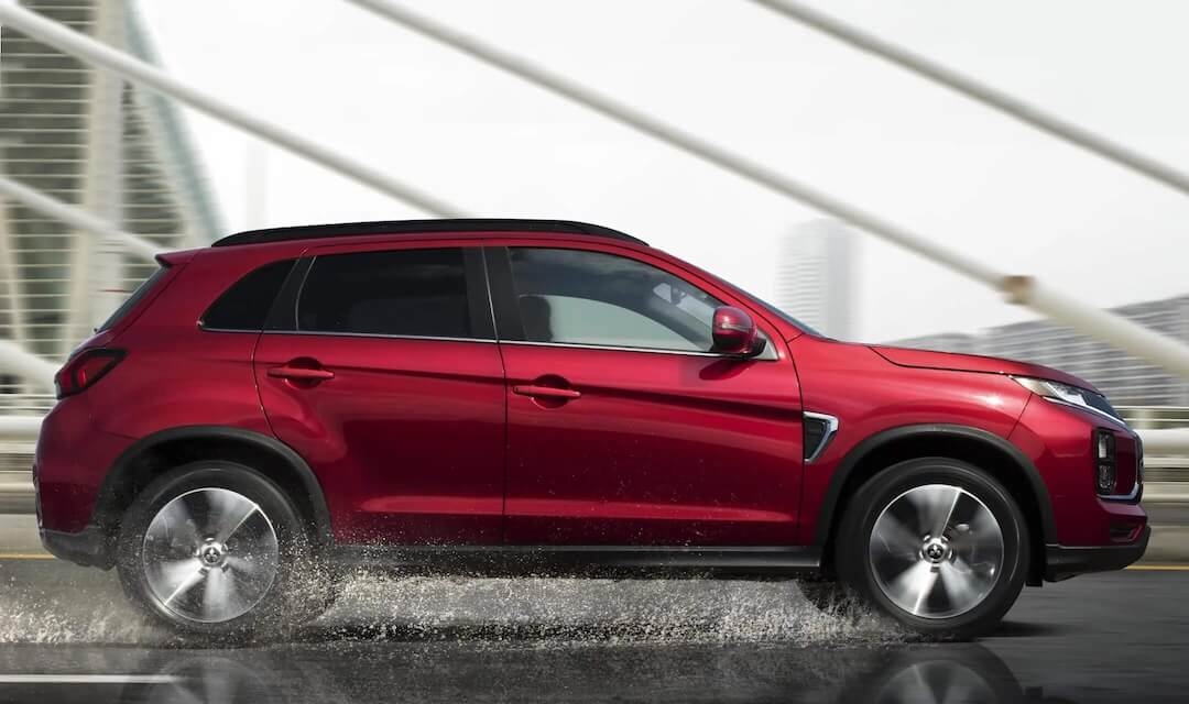 Vue latérale du Mitsubishi RVR 2025 rouge roulant sous la pluie.